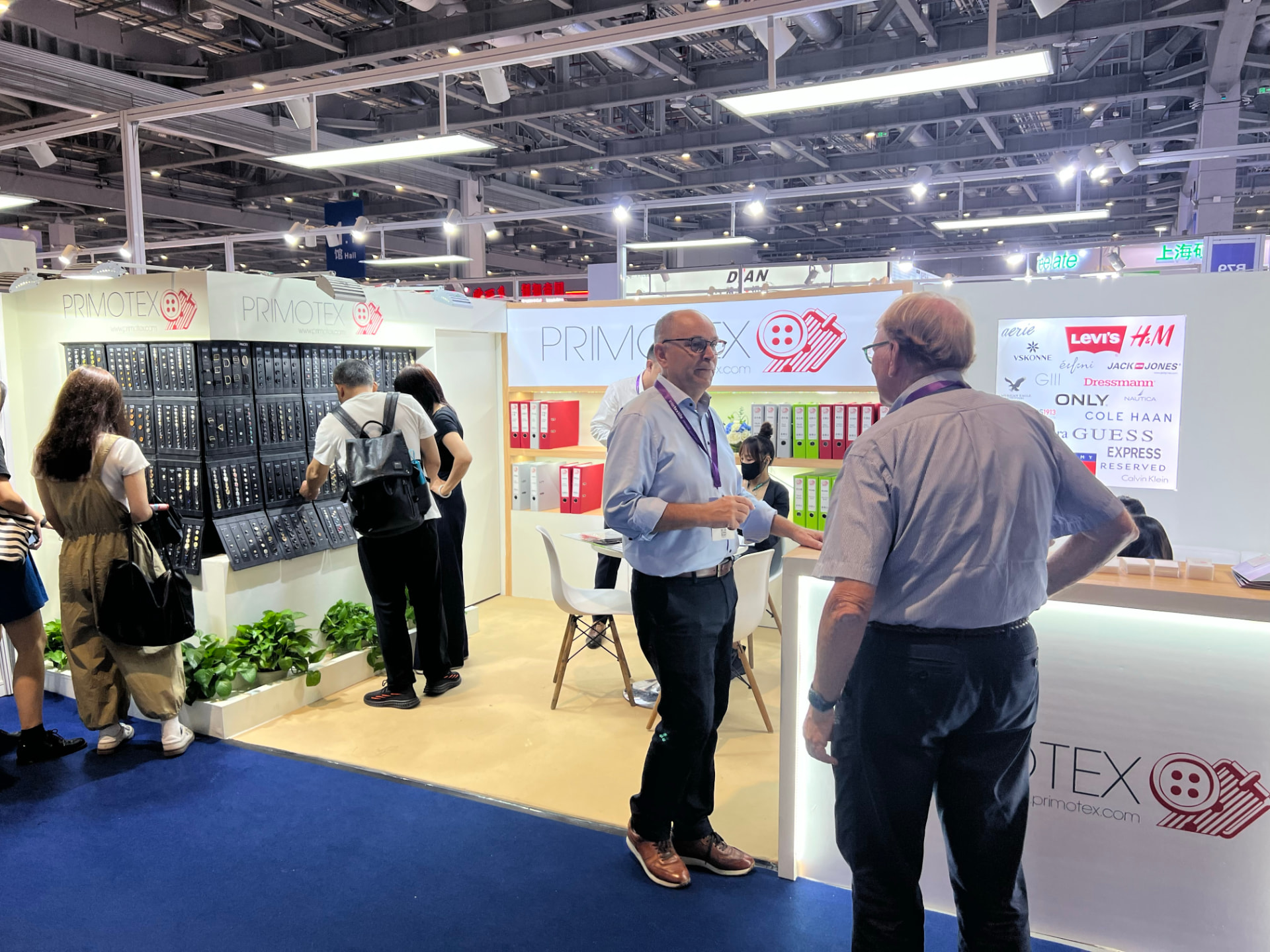 Primotex booth at Intertextile Shanghai Apparel Fabrics, visitors browsing the button sample wall under the Primotex sign