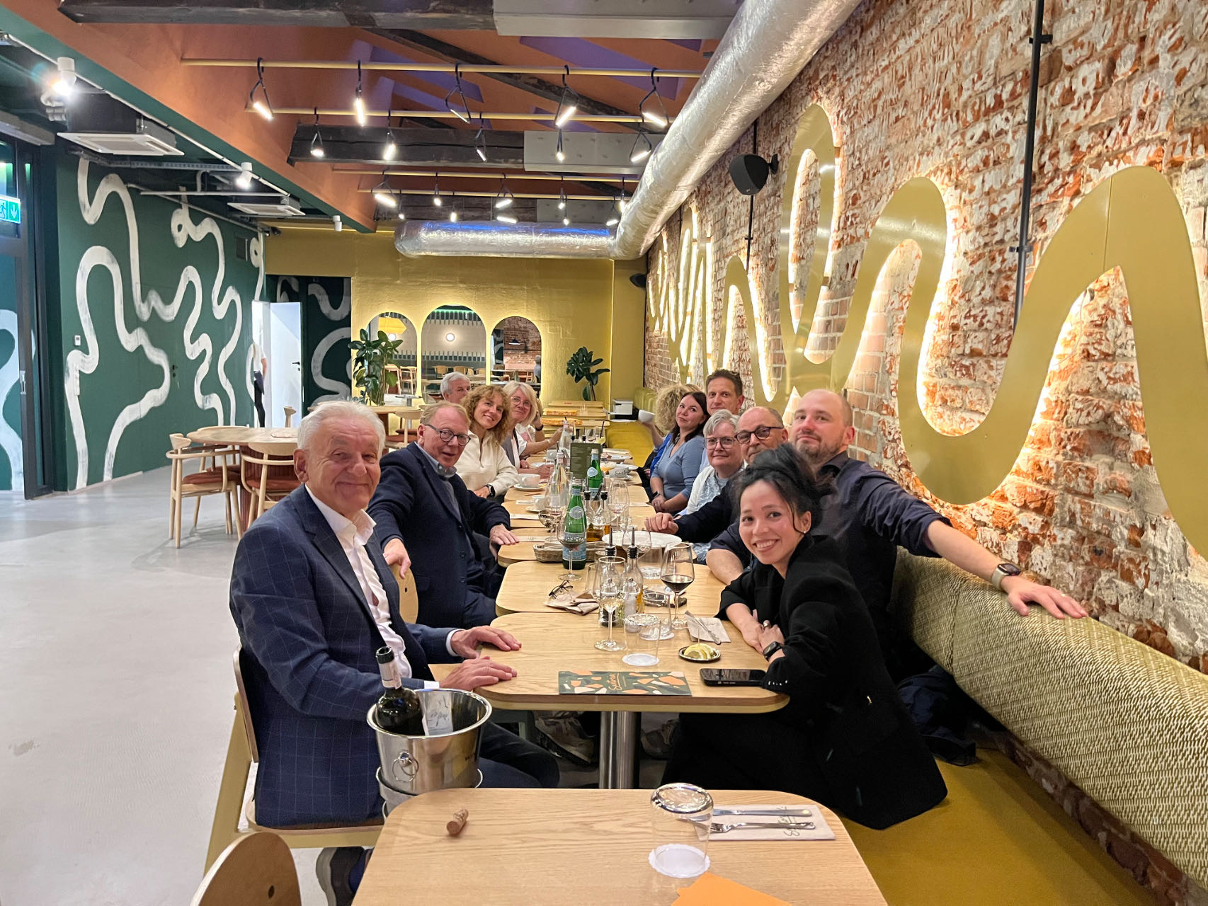 Primotex team members gathered around a dinner table in a restaurant in Łódź, seen from the opposite end of the table